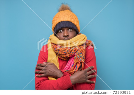 African american mature man in yellow scarf and hat freezing in warm clothing. African american mature man in yellow scarf and hat freezing in warm clothing. 72393951