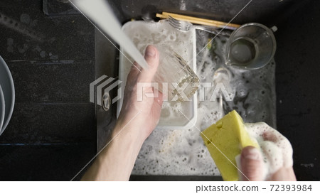 Washing dirty dishware in black sink 72393984