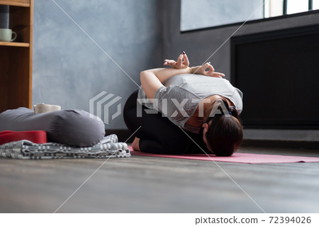 young woman sitting in child pose on a yoga mat young woman sitting in child pose on a yoga mat 72394026
