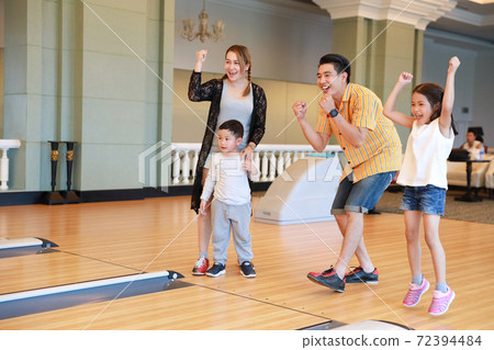 group of happiness asian family father, mother, son and daughter playing bowling in sport club with happy smiling face during holiday vacation 72394484