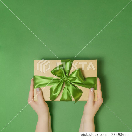 Woman holding present box on green table Woman holding present box on green table 72398623