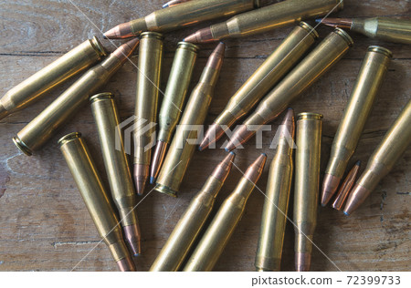 Many carbine bullets on old wooden background Many carbine bullets on old wooden background 72399733
