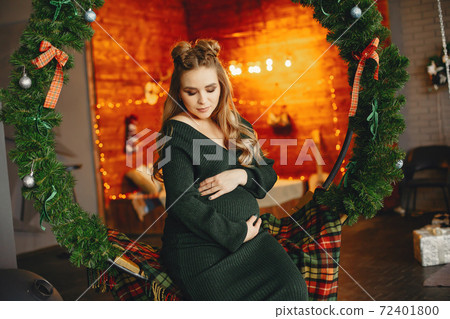 Elegant young lady sitting near Christmas tree Elegant young lady sitting near Christmas tree 72401800