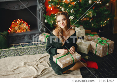 Elegant young lady sitting near Christmas tree Elegant young lady sitting near Christmas tree 72401802