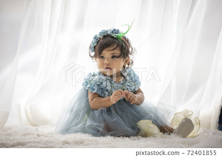 Lovely cute little Asian girl in a blue dress is playing merrily and happily in her own home, promoting her skills and creativity. 72401855