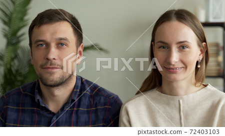 Portrait of a young couple sitting on a sofa. Couple looking at the camera 72403103