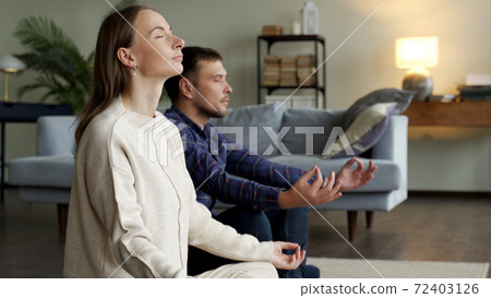 Online yoga practice. Couple meditating at home near laptop Online yoga practice. Couple meditating at home near laptop 72403126