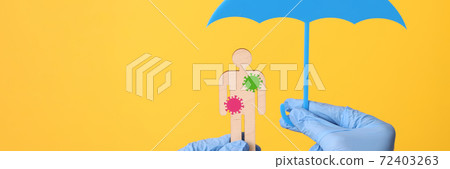 Hands in gloves hold wooden man with stickers bacteria and an umbrella 72403263