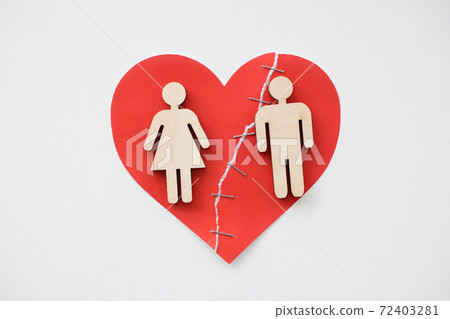 On the glued broken heart, there are figurines of man and woman. On the glued broken heart, there are figurines of man and woman. 72403281