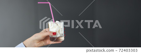 Female hand holds glass with sugar cubes and straw 72403303
