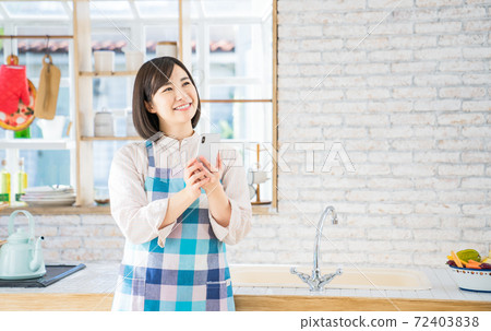 A young woman using a smartphone in the kitchen A young woman using a smartphone in the kitchen 72403838