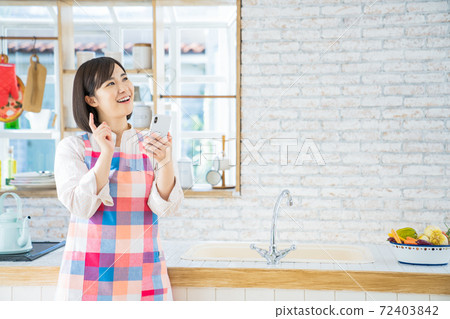 A young woman using a smartphone in the kitchen A young woman using a smartphone in the kitchen 72403842