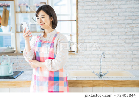 A young woman using a smartphone in the kitchen A young woman using a smartphone in the kitchen 72403844