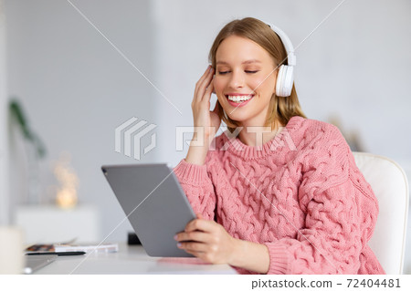 Cheerful female with tablet listening to music. Cheerful female with tablet listening to music. 72404481