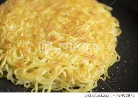 Up of Chinese noodles baked in a frying pan in a golden color [black background] 72408976