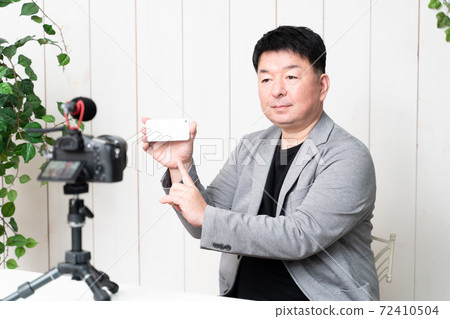 Middle-aged man shooting a video Middle-aged man shooting a video 72410504