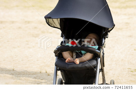 Copy space with baby sleeping in a black stroller in the park 72411655