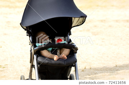 Copy space with baby sleeping in a black stroller in the park 72411656