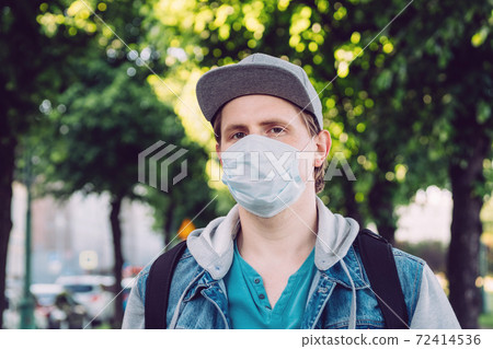 Caucasian man thirty years in medical mask walks through the park in summer Caucasian man thirty years in medical mask walks through the park in summer 72414536