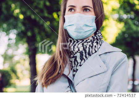 Caucasian girl in a medical mask walks in the summer park 72414537