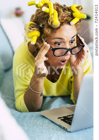 Funny and nice pretty woman surprised looking a laptop computer - yellow colors and curles foe home made getting ready hair style and concept of online shopping sales like black friday or cyber monday 72414913