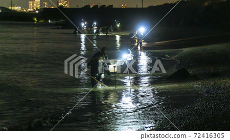 在靜岡縣岩田市天龍河河口，一位漁民依靠照明用手網sc著海灘。 72416305