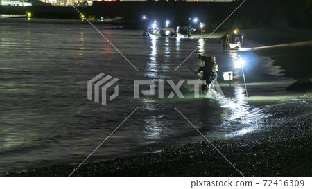 At the mouth of the Tenryu River in Iwata City, Shizuoka Prefecture, fishermen scoop up the beach with a net, relying on lighting. 72416309