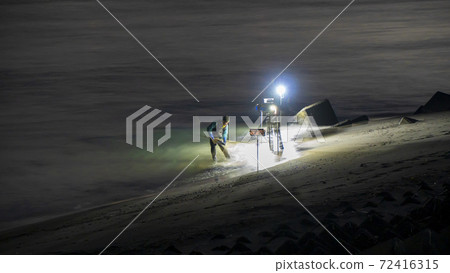 在靜岡縣岩田市天龍河河口，一位漁民依靠照明用手網sc著海灘。 72416315