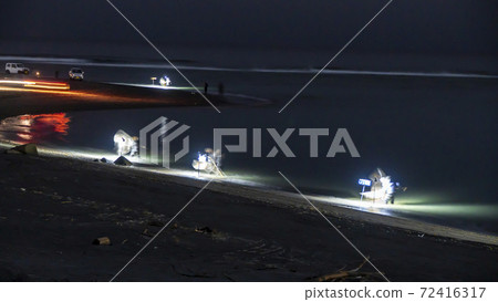 At the mouth of the Tenryu River in Iwata City, Shizuoka Prefecture, fishermen scoop up the beach with a net, relying on lighting. 72416317