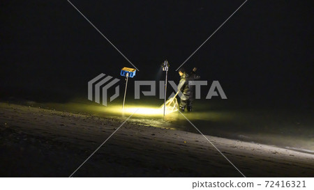 在靜岡縣岩田市天龍河河口,一位漁民依靠照明用手網sc著海灘。 在靜岡縣岩田市天龍河河口,一位漁民依靠照明用手網sc著海灘。 72416321