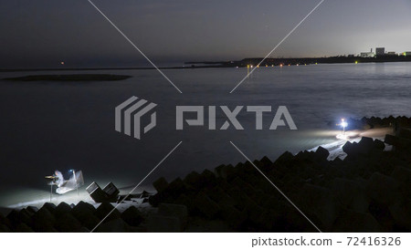 在靜岡縣岩田市天龍河河口，一位漁民依靠照明用手網sc著海灘。 72416326