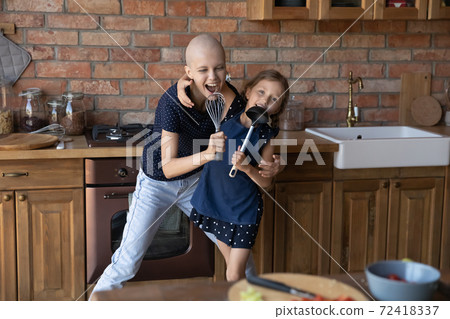 Happy hairless mother and little daughter having fun in kitchen 72418337