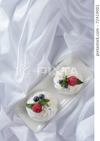 Dessert Pavlova with raspberries, blueberries and mint on a white fabric. 72419001
