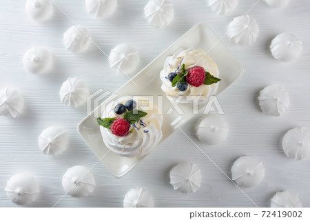 Dessert Pavlova with raspberries, blueberries and mint on a white table. 72419002