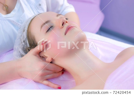 Cosmetologist massagist doctor makes myoplastic neck massage to young woman. 72420454