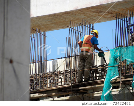 MALACCA, MALAYSIA -MARCH 2, 2020: Construction workers working at height at the construction site. They are supplied with harnesses and other safety equipment to prevent them from having an accident. MALACCA, MALAYSIA -MARCH 2, 2020: Construction workers working at height at the construction site. They are supplied with harnesses and other safety equipment to prevent them from having an accident. 72422491