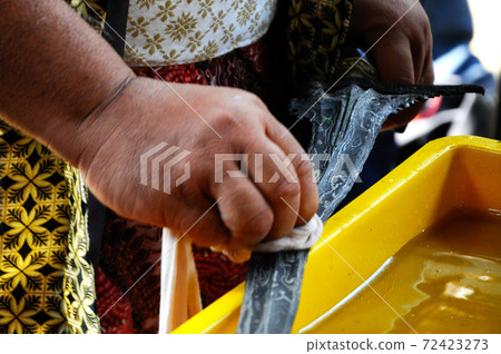 SEREMBAN, MALAYSIA -MAY 01, 2017: A man demonstrate traditional way to clean kris using special chemical and calamondin (citrus microcarpa). A ritual with mystic believe. SEREMBAN, MALAYSIA -MAY 01, 2017: A man demonstrate traditional way to clean kris using special chemical and calamondin (citrus microcarpa). A ritual with mystic believe. 72423273