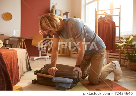 Man closing his suitcase Man closing his suitcase 72424640