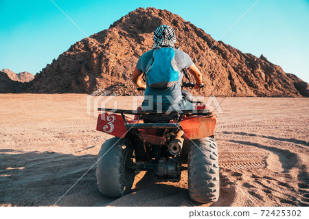 A Bedouin on an All-terrain vehicle er the dunes of the Egyptian desert A Bedouin on an All-terrain vehicle er the dunes of the Egyptian desert 72425302