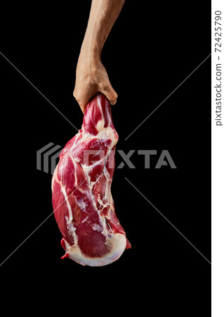 Hand of a butcher holds raw leg of lamb 72425790