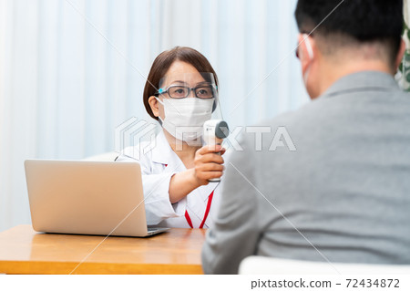 A nurse who attaches a face shield and measures the temperature 72434872