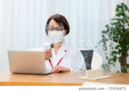 A nurse who attaches a face shield and measures the temperature 72434873