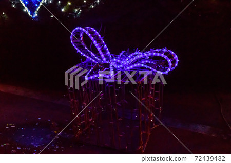 Illuminated Christmas gift box at night. Decoration for Christmas and New Years holidays in a city park Illuminated Christmas gift box at night. Decoration for Christmas and New Years holidays in a city park 72439482
