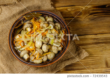 Delicious marinated mushrooms with carrot, onion and spices in ceramic bowl on wooden table. Top view Delicious marinated mushrooms with carrot, onion and spices in ceramic bowl on wooden table. Top view 72439543