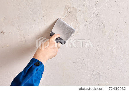 Repairman is finishing wall at home with putty and work tool. 72439982
