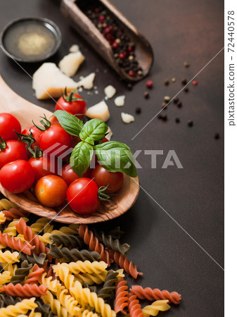 Fusilli with cherry tomatoes in wooden bowl with pepper in scoop and parmesan cheese with salt  72440578