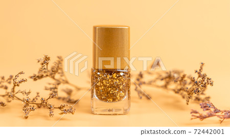 Nail polish of beautiful gold colors on orange background. 72442001