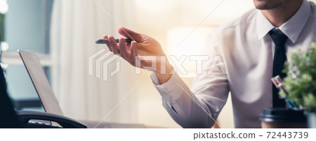 Businessman sitting at the desks with holding a pen and point it forward. Businessman sitting at the desks with holding a pen and point it forward. 72443739