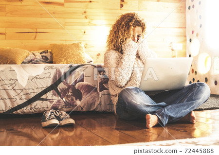 Surprised and scared caucasian woman looking a computer laptop monitor sit down on the wooden floor at home or hotel Surprised and scared caucasian woman looking a computer laptop monitor sit down on the wooden floor at home or hotel 72445888