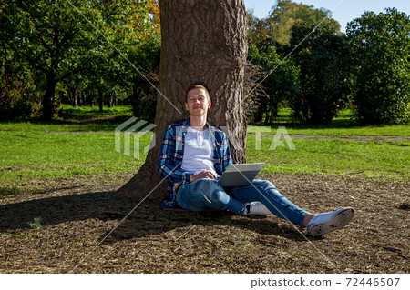 Guy working on laptop in the park 72446507
